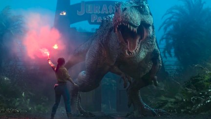 In a scene from Jurassic Park: Survival, a woman holds a flare in front of a roaring T-rex.