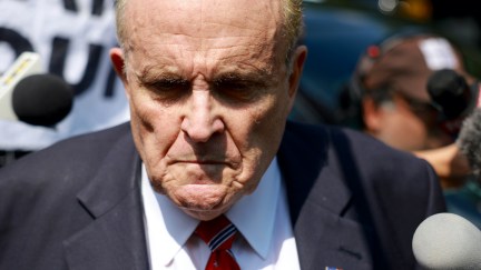 Rudy Giuliani looks sad in a crowd of reporters