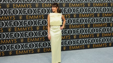 Aubrey Plaza wears a yellow dress with a square front and a giant pin through the top at the 2023 Emmy Awards.