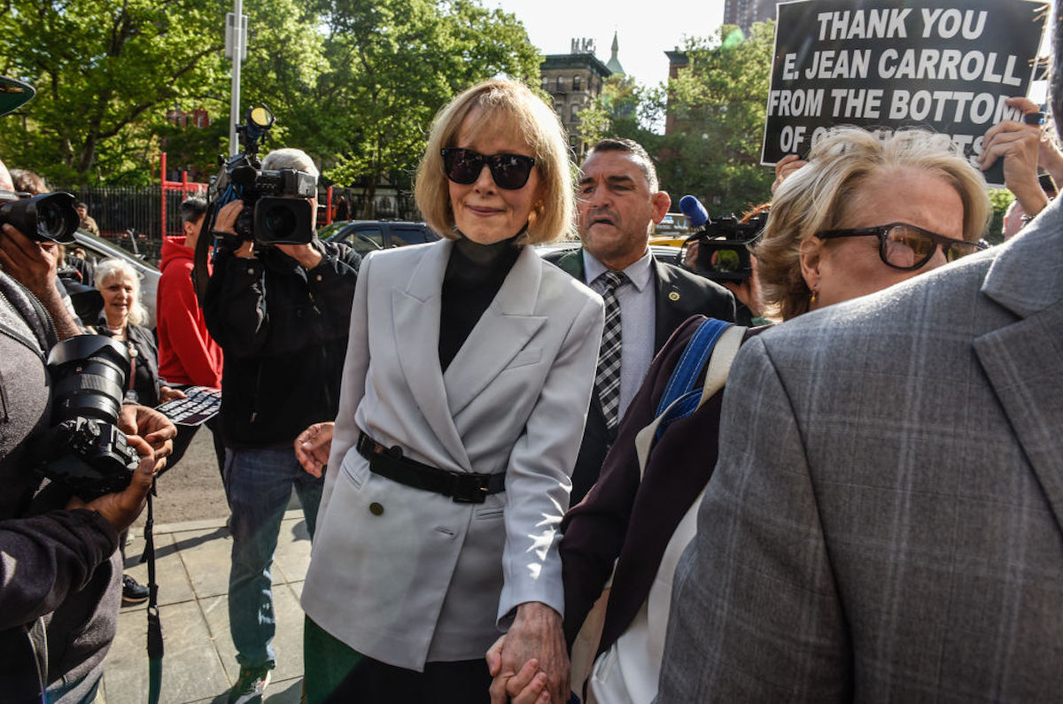 E. Jean Carroll arrives for her civil trial. A person behind her holds a sign reading "Thank you E. Jean Carroll from the bottom of our hearts"