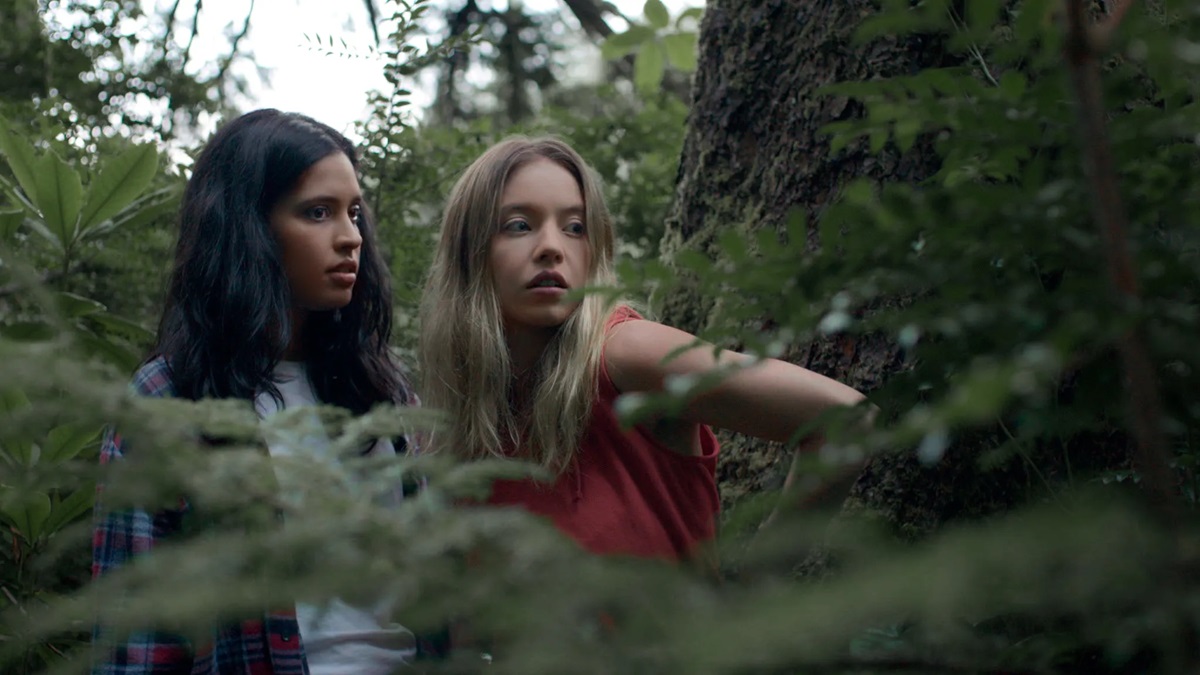 Otmara Marrero and Sydney Sweeney peer through the trees in Clementine