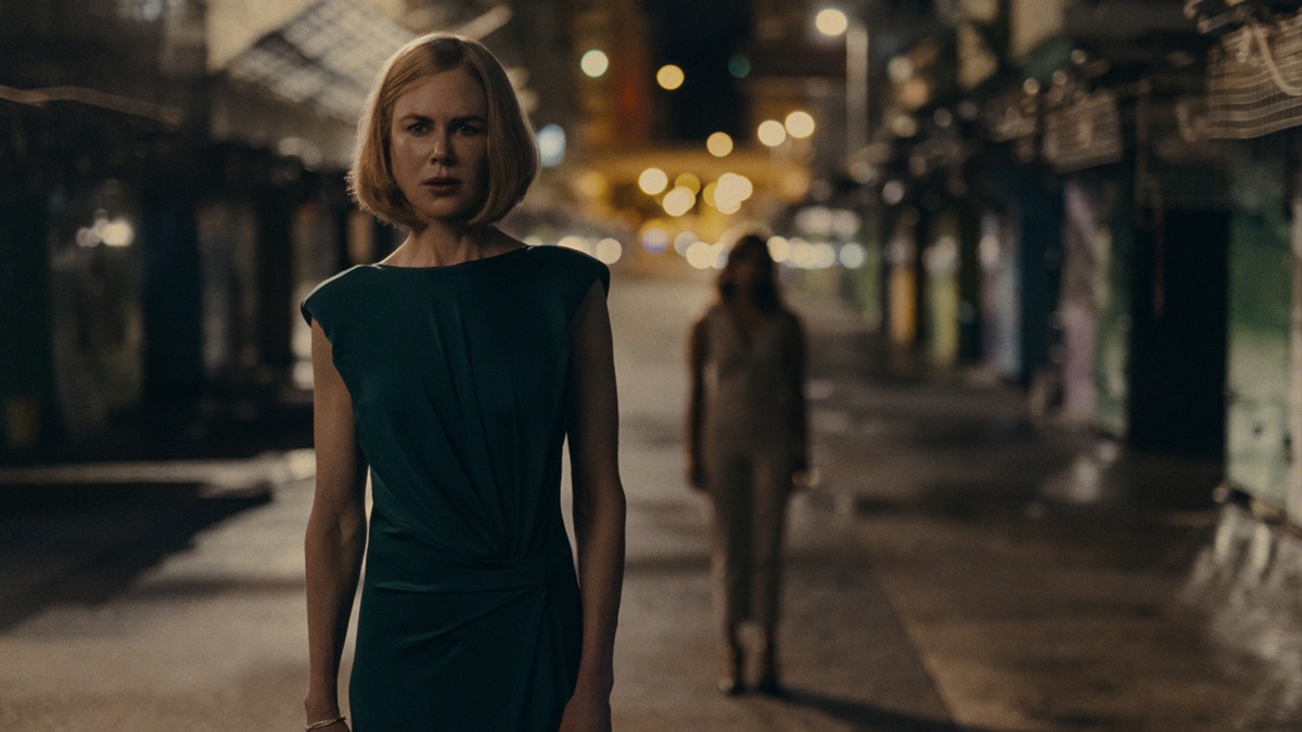 Nicole Kidman walks down a dark street with someone following behind her in Expats