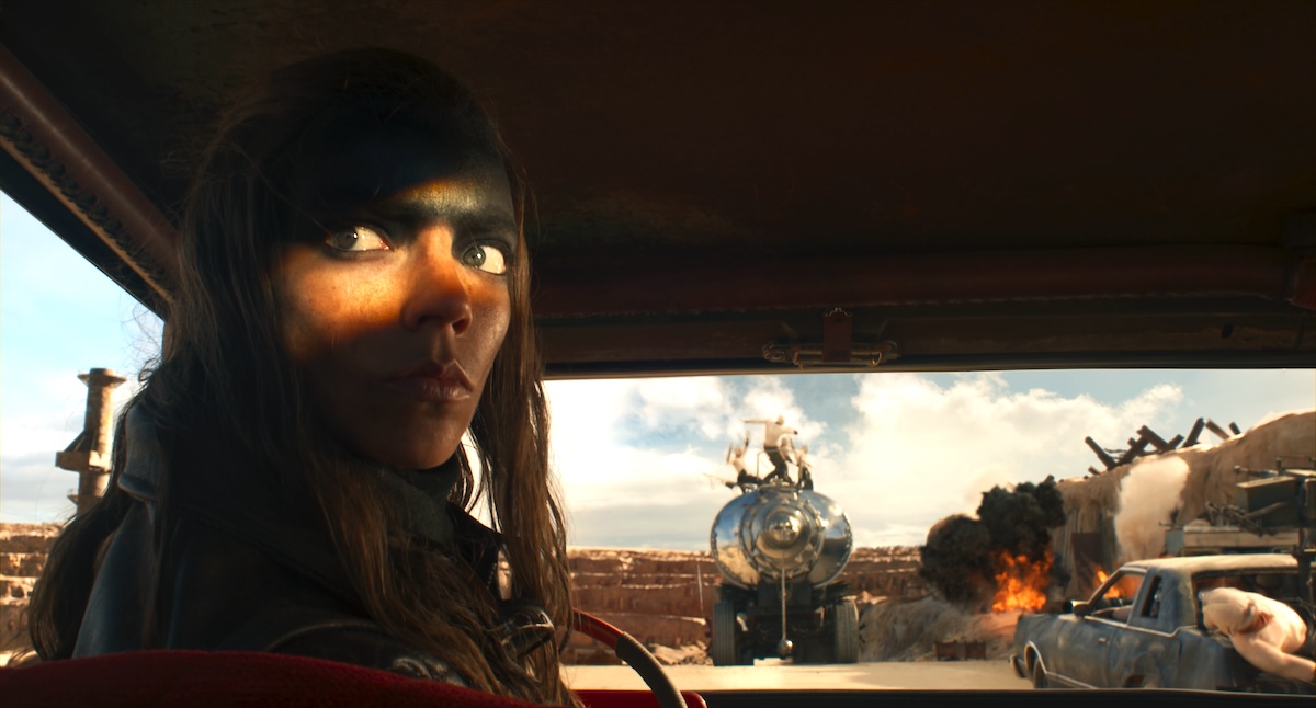 Furiosa looks over her shoulder while backing up a truck.