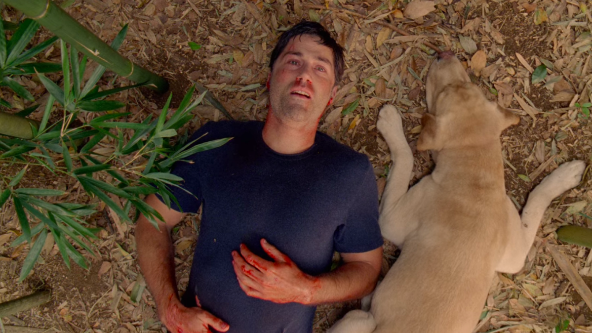 Jack Shephard lays on the ground with his dog