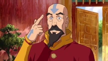 Tenzin points to his bald head in 