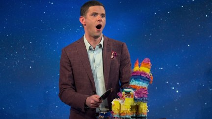 Mikey Day laughs as he cuts a pinata-shaped cake.