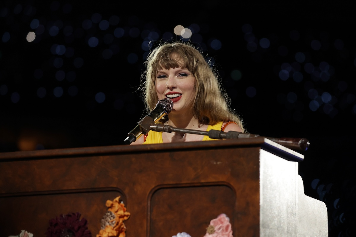 Taylor Swift sitting at a piano and smiling