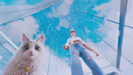 A young woman and a cat stand against blue sky in 