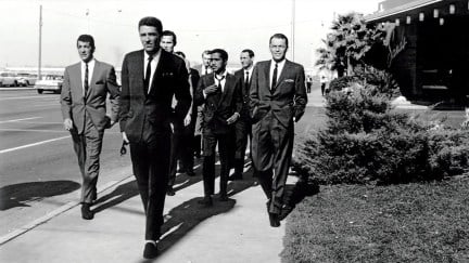 Men in suits walk down the street in 