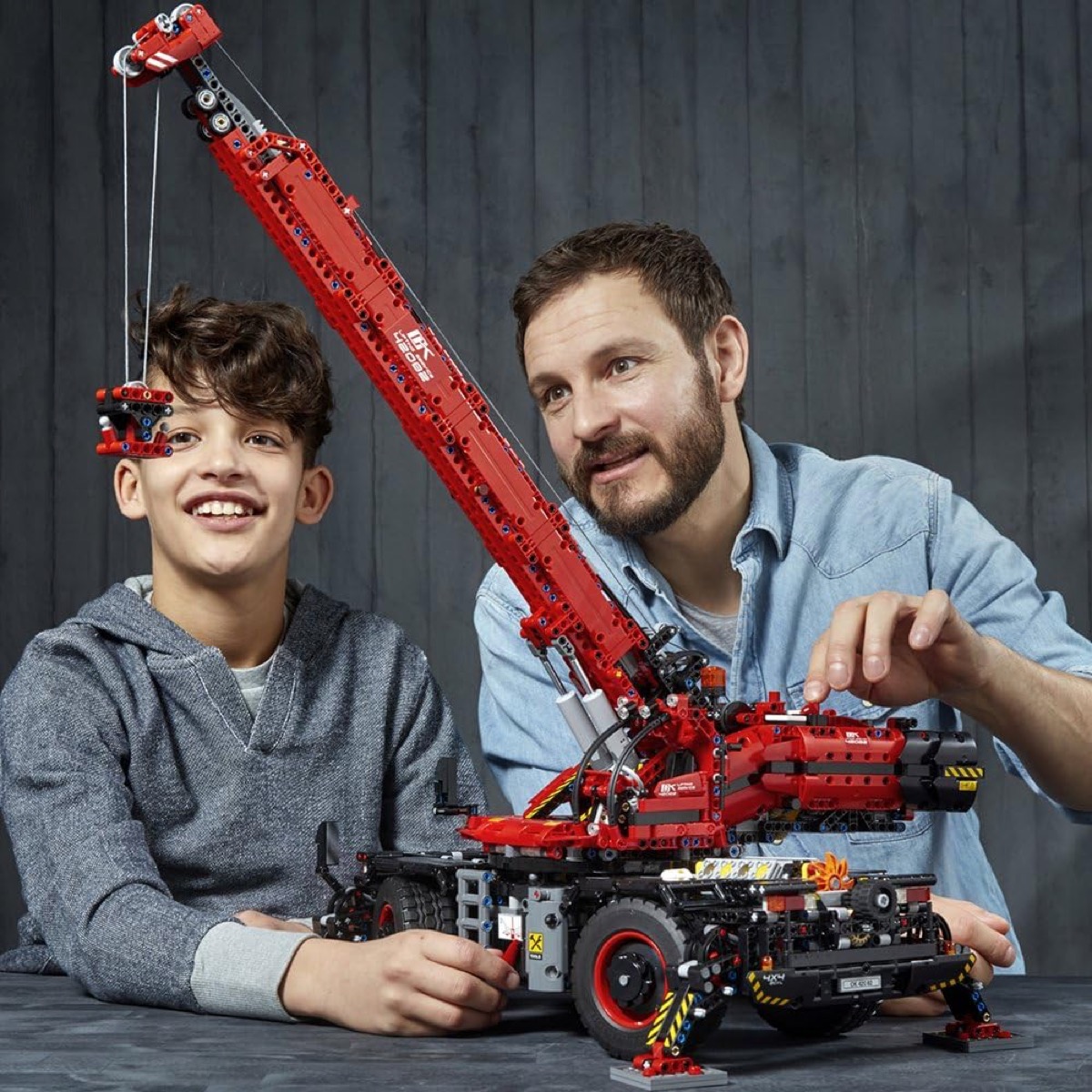 A father and son play with the The Rough Terrain Crane from LEGO