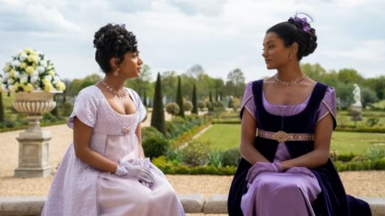 Sharma Sisters, Bridgerton sat facing one another in purple dresses Simone Ashley and Charithra Chandran