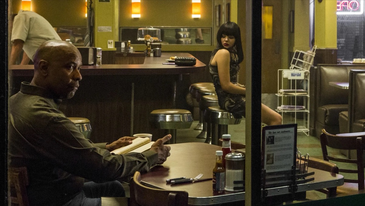 A man sits at a desk with a typewriter while a young woman looks on in "The Equalizer" 