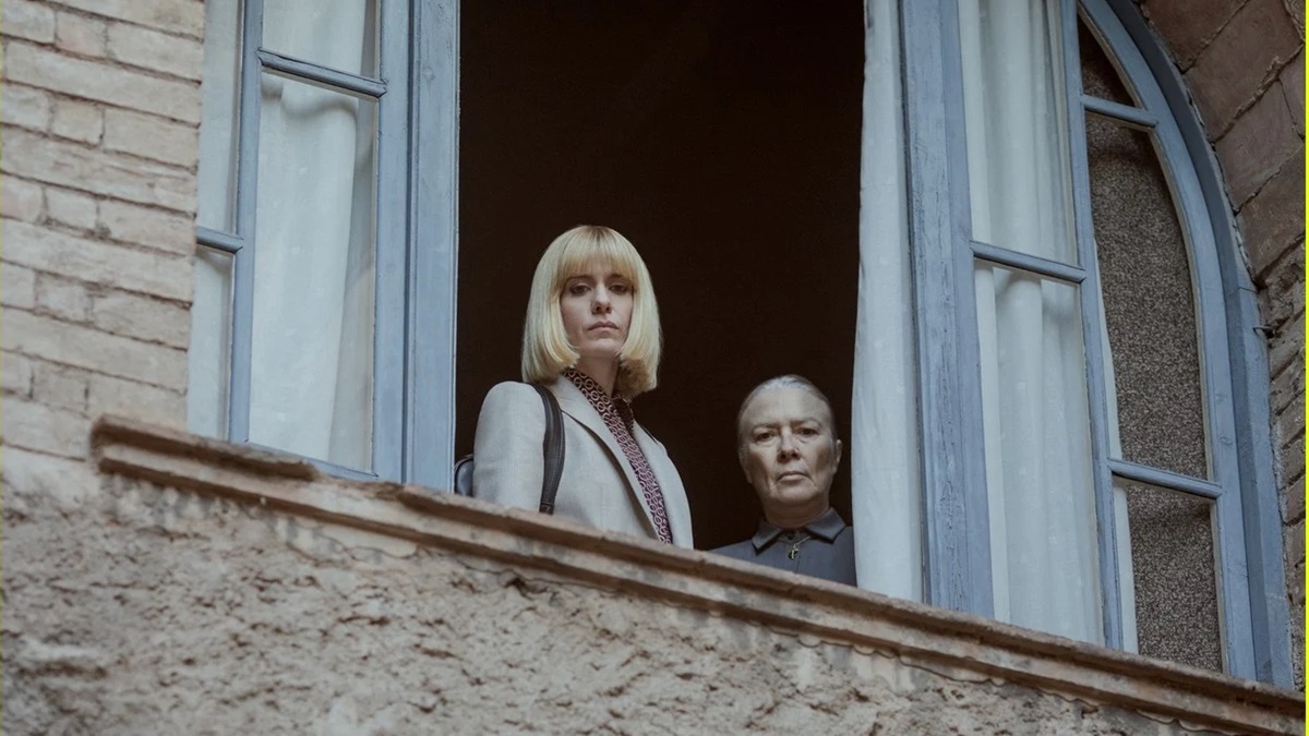 Two women look down from an open window