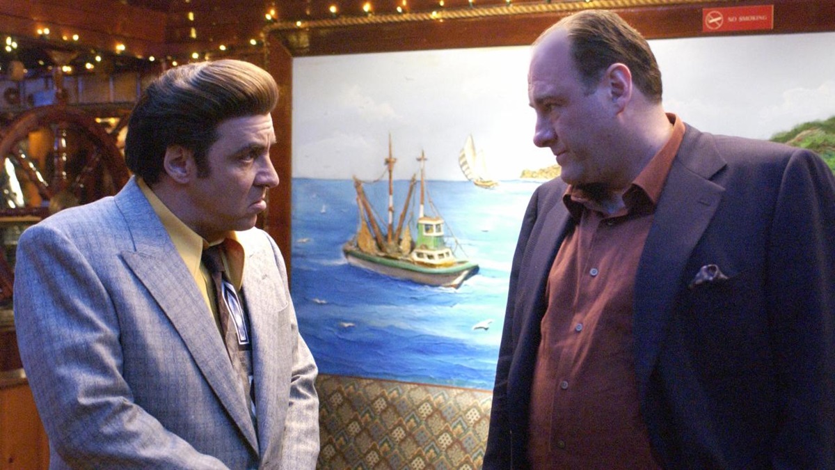 Silvio and Tony chat in front of a painting of a boat