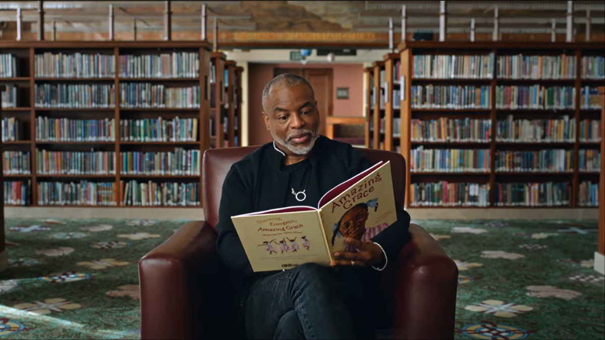 LeVar Burton sits in a library reading a book in this still from 'Butterfly in the Sky: The Story of Reading Rainbow'.