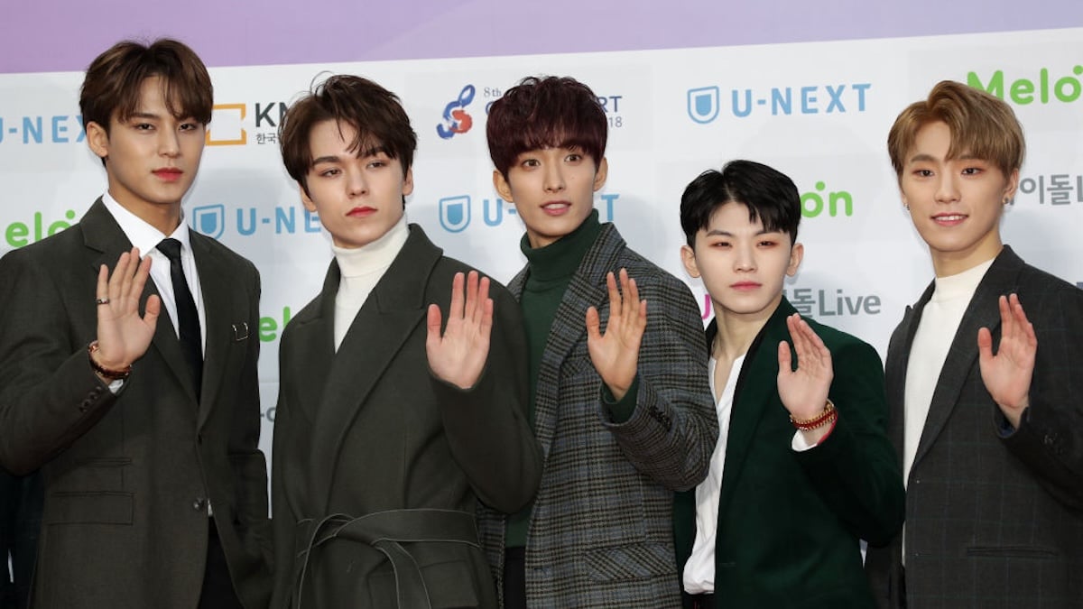 K-pop band Seventeen waves at photographers.