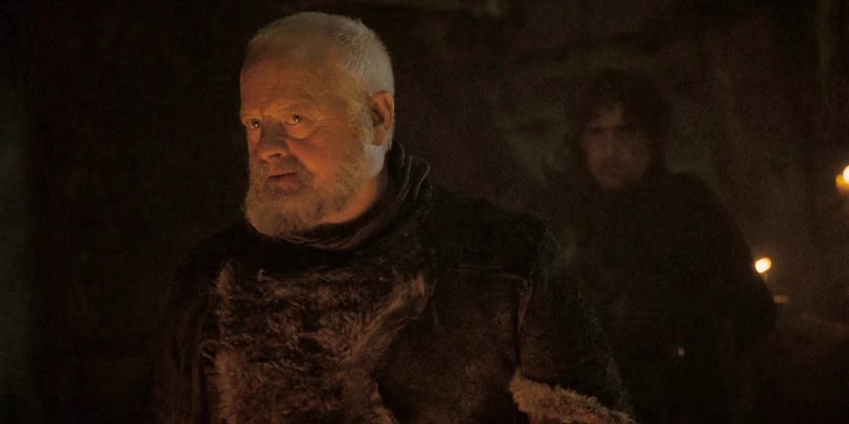 Craster looks menacingly at an offscreen foe in the firelight in "Game of Thrones" 