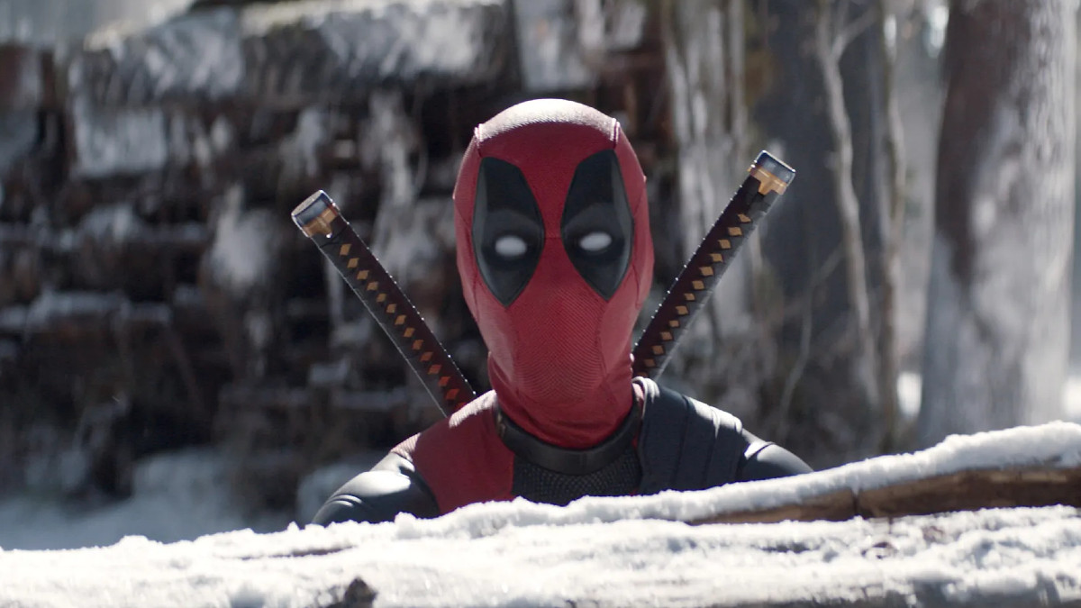 Deadpool sitting behind a snow-covered tree trunk in the Deadpool & Wolverine trailer