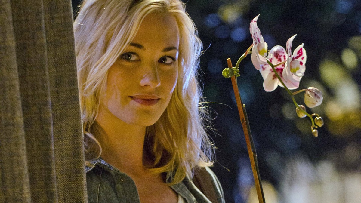 Hannah McKay stands with an orchid behind her