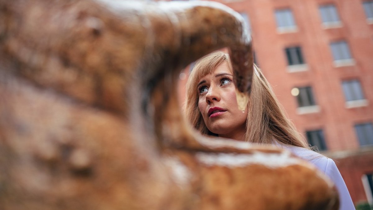 A young blonde woman facing a mostly unseen slimy monster