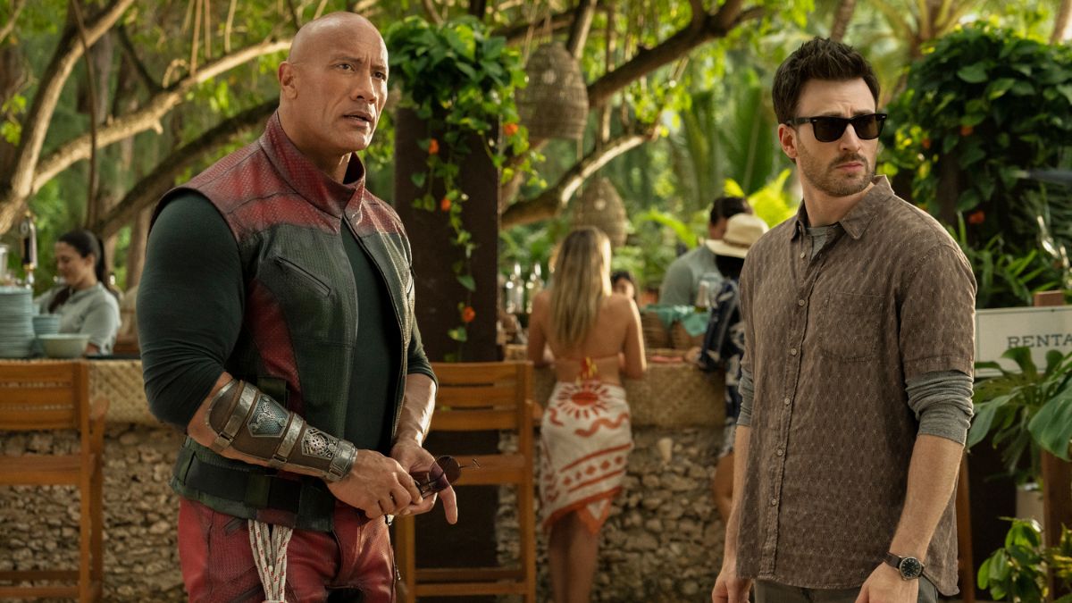 Dwayne Johnson and Chris Evans standing in the middle of a tropical bar in a shot from Red One