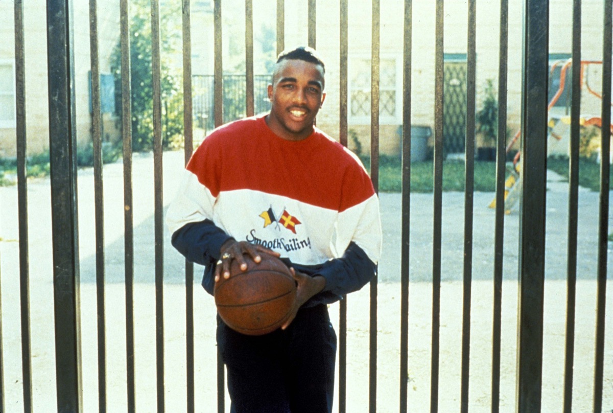 A young man holds a basketball and smiles in "Hoop Dreams" 