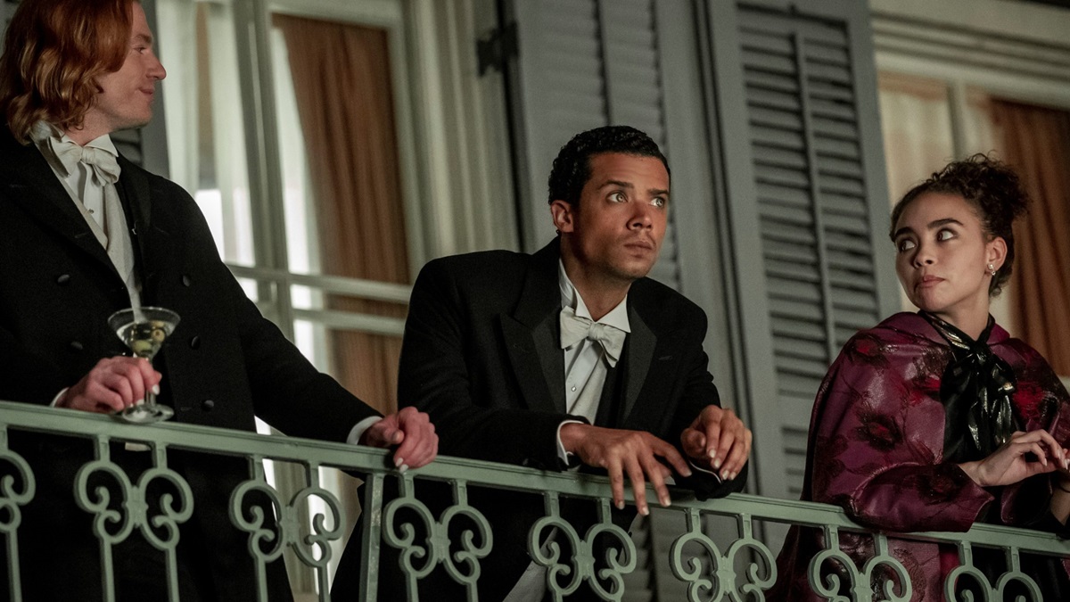 Two men and a young woman stand on a balcony