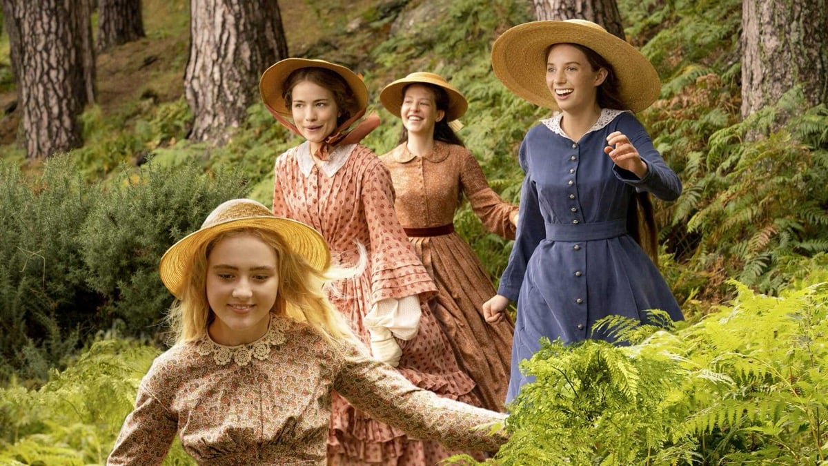 A group of young women traipse through the woods in "Little Women"