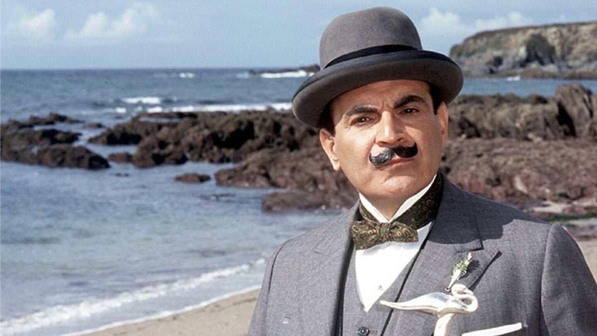 A mustachioed man stands by the seaside in "Poirot"