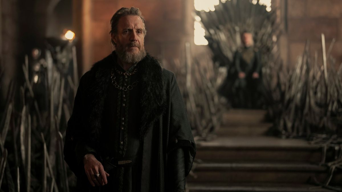 Tom Glynn-Carney as King Aegon II on the Iron Throne and Rhys Ifans as Ser Otto Hightower Hand of the King presiding over court in the throne room in House of the Dragon season 2 episode 1