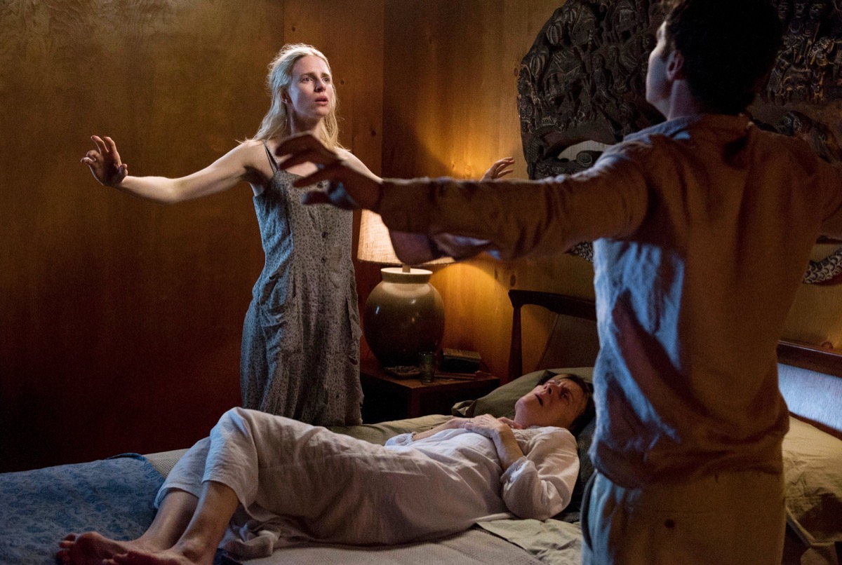 Two people spread their arms on either side of a bed that someone is laying in in "The OA" 