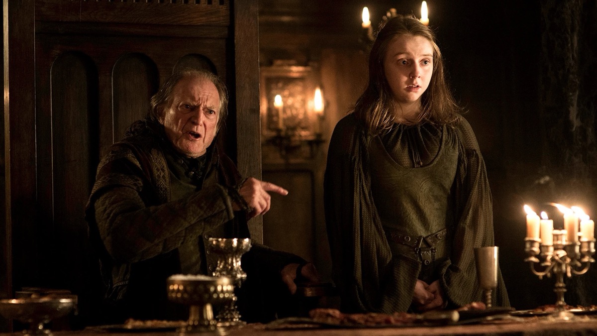 Seated Walder Frey points at a scared young girl in "Game of Thrones"