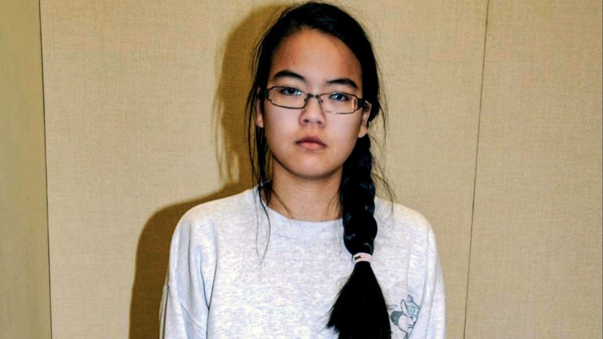 A young woman stands stonefaced in front of a bare wall in "What Jennifer Did"