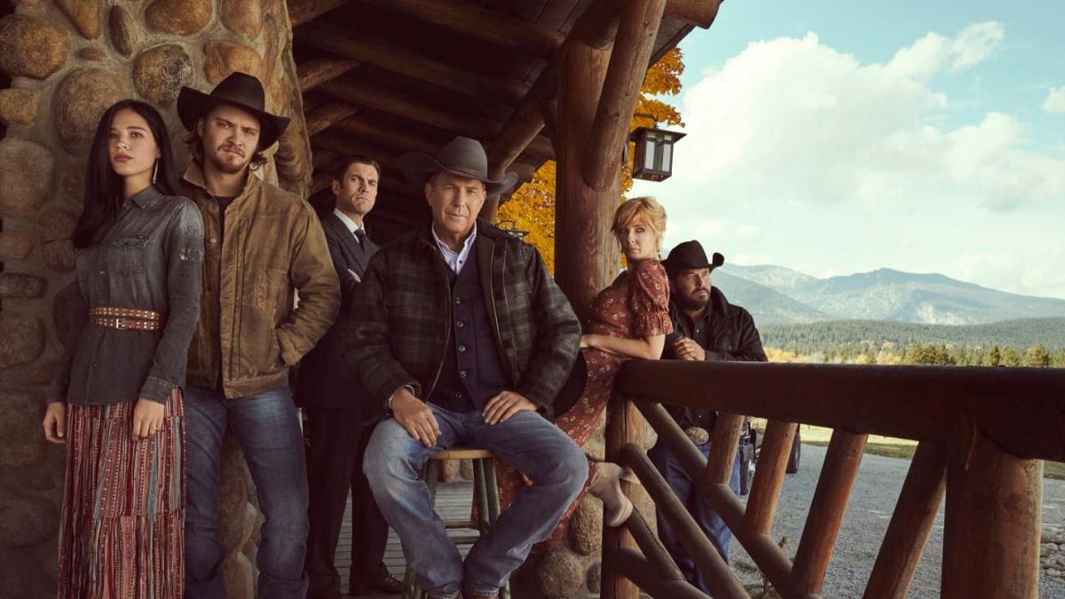 The main cast of the Yellowstone tv show posing outside the Dutton ranch