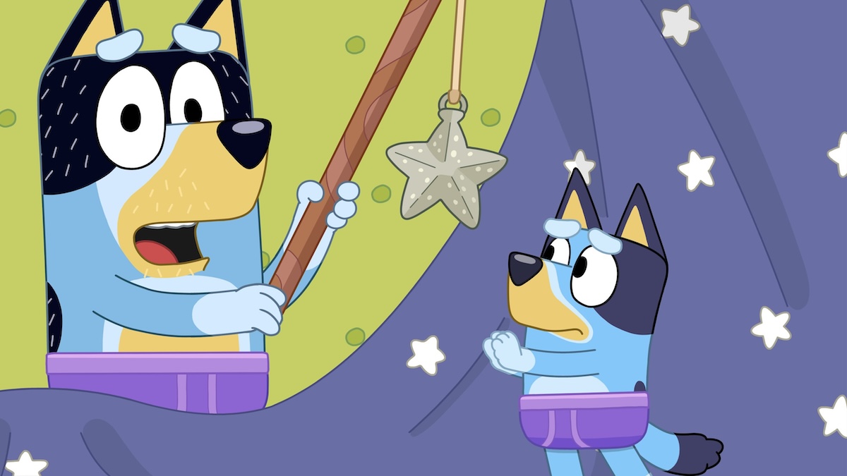 Bandit holds a fishing rod with a star hanging from it, which Bluey is trying to catch. They're both wearing purple briefs.