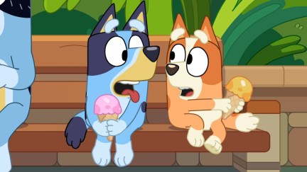 Bluey and Bingo sit on a park bench, eating ice cream.