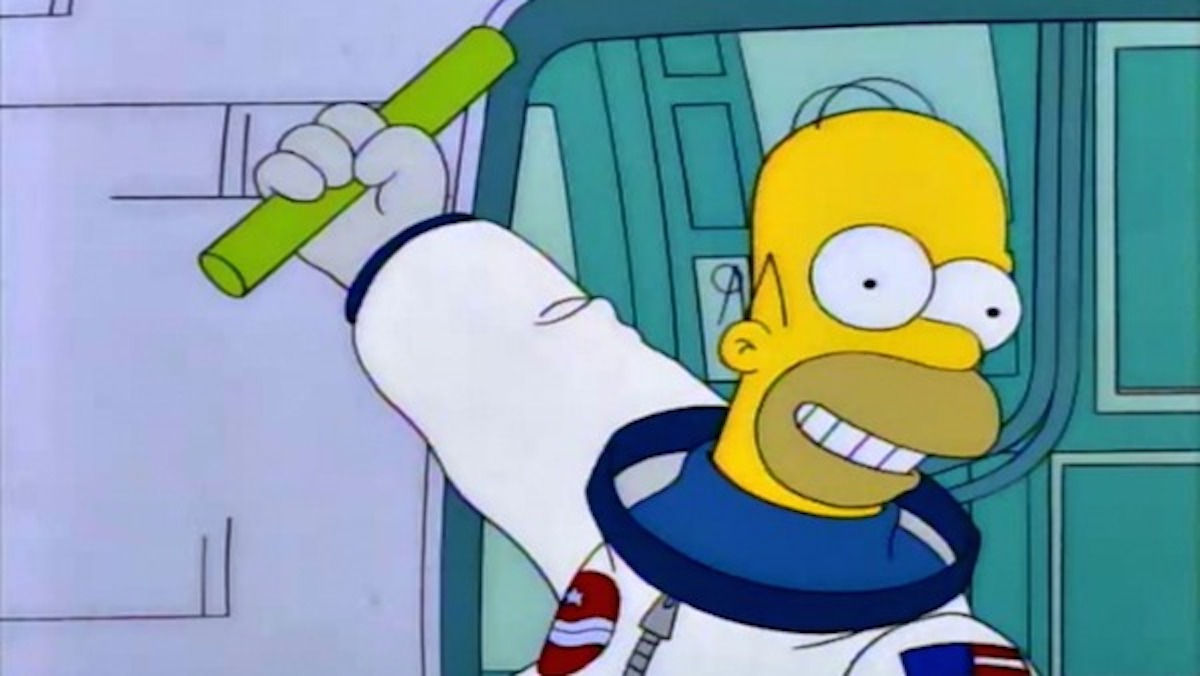 Homer Simpson dressed as an astronaut holds up an inanimate carbon rod