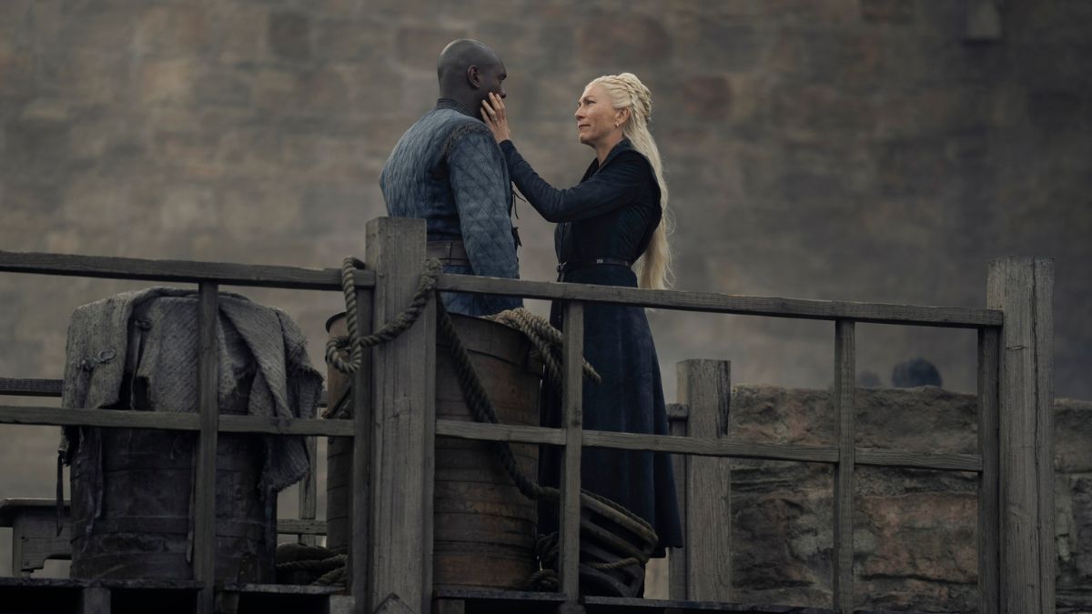 Eve Best as Rhaenys Targaryen touches the face of Abubakar Salim as Alyn of Hull while standing on a wooden pier in House of the Dragon season 2 episode 4