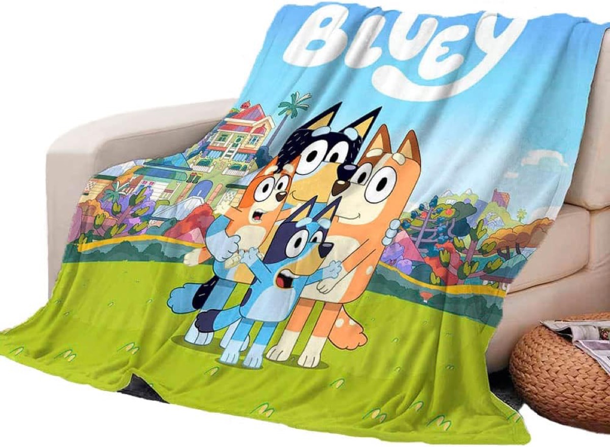 Bluey and family pictured on a blanket laying on a sofa 