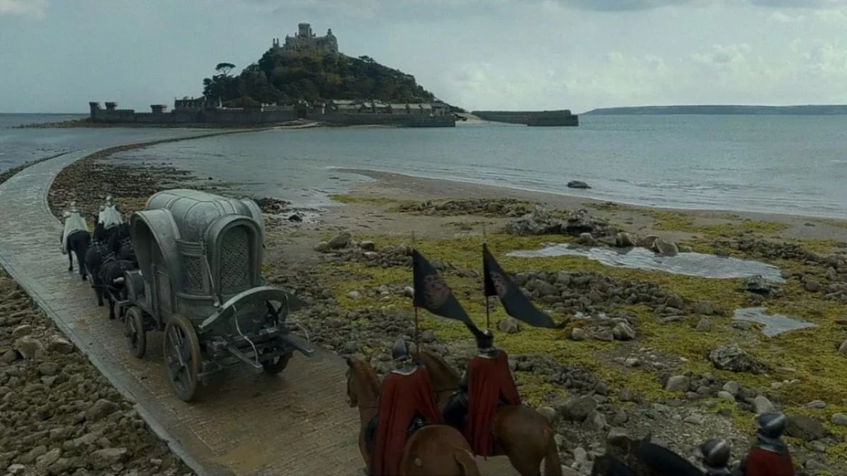 A procession of the King's carriage rides on a road leading to a castle on the island of Driftmark in House of The Dragon