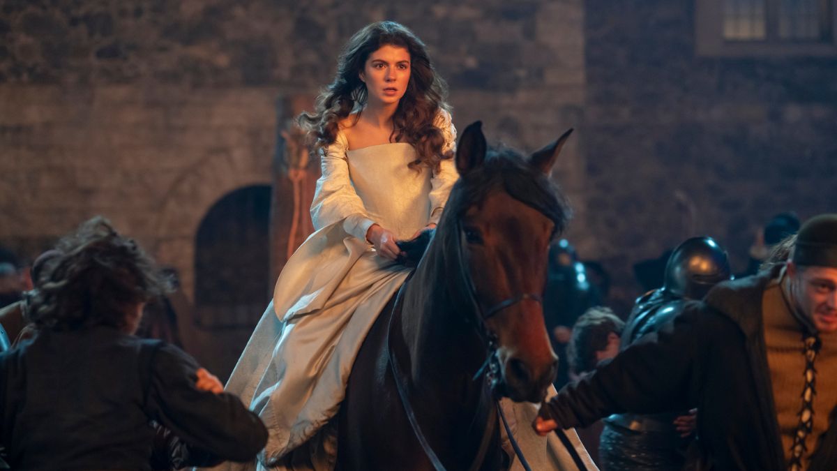 Emily Bader as Jane Grey rides away on a horse through a crowd in My Lady Jane
