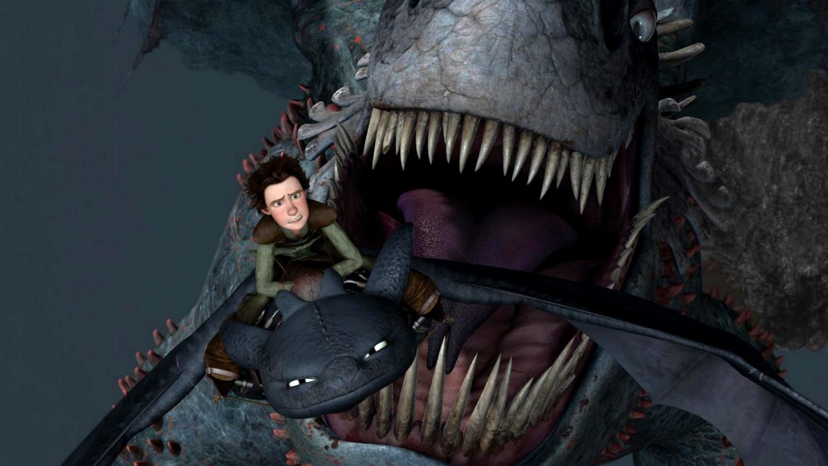 Hiccup rides Toothless away from the jaws of a monster