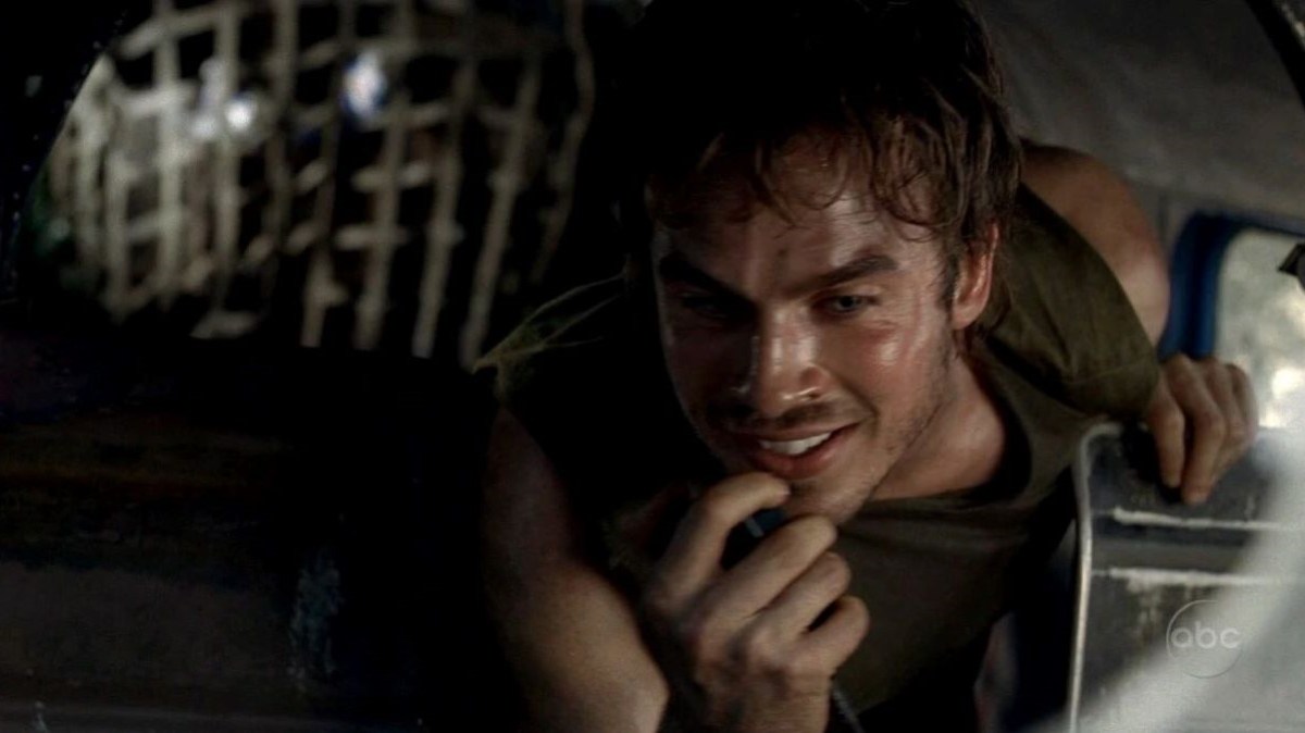 Ian Somerhalder as Boone in a scene from ABC's 'Lost.' He is a young, white man with shaggy dark hair wearing a dark green tank top. He's crouching in a crashed plane speaking happily into a radio that still works.