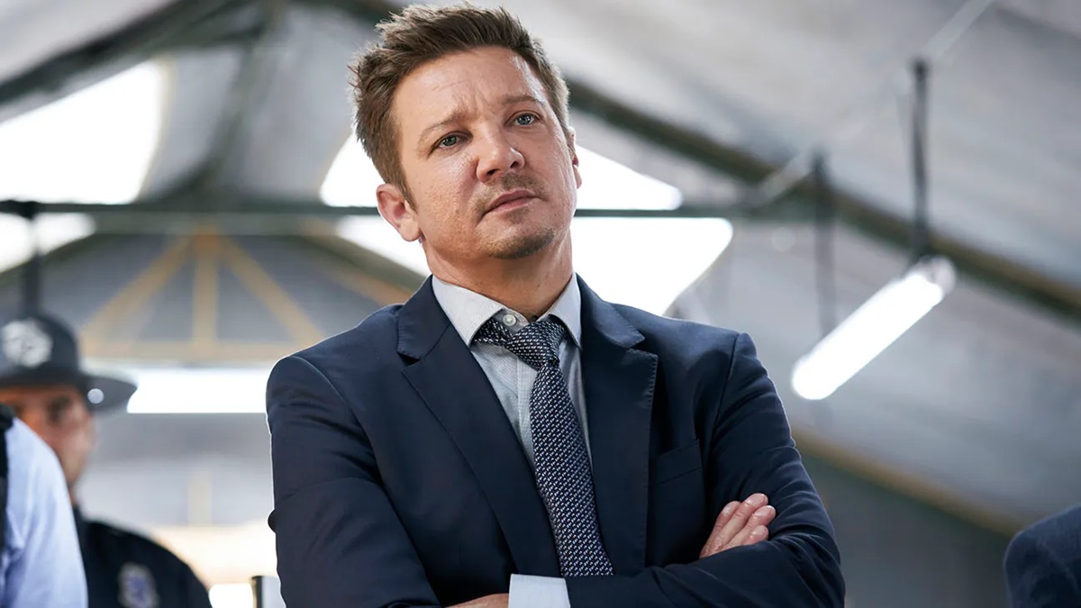 Jeremy Renner folds arms across chest and looks annoyed