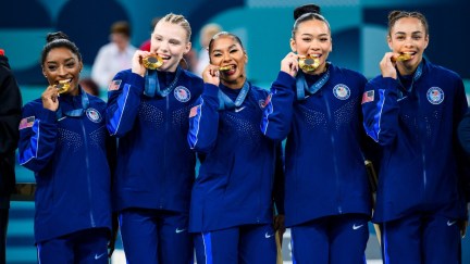 The 2024 Olympics Women's Gymnastics Team bites their gold medals after winning the team event