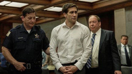 A man in a courtroom is led away by a police officer in 