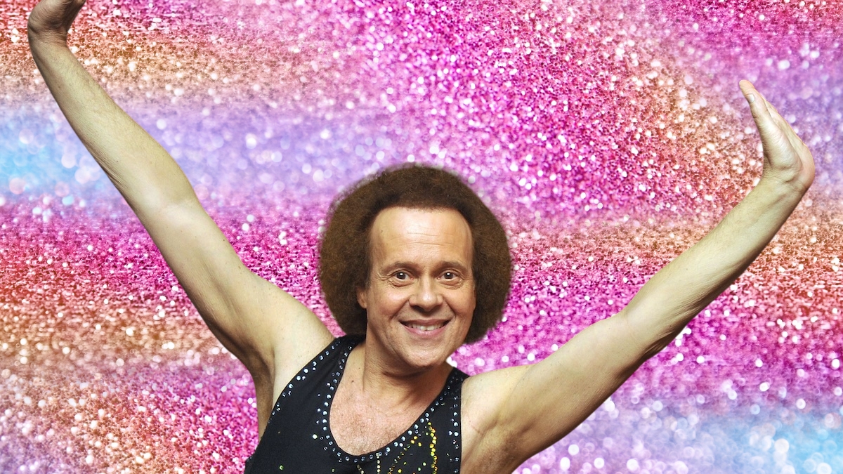 Richard Simmons poses and grins against a glittery background