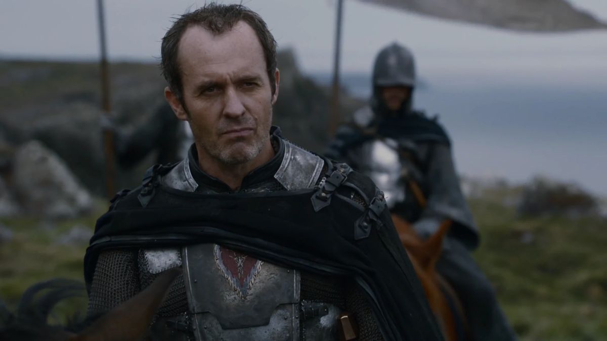 Stephen Dillane as Stannis Baratheon rides a horse with a soldier holding his banner behind him in Game of Thrones