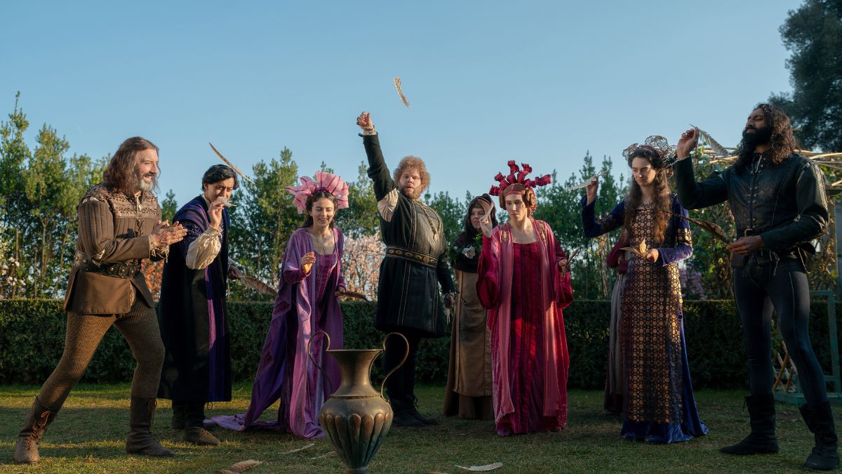 A bunch of people dressed in 13th century Italian garb are in a farden, playing a game of landing a feather into a vase