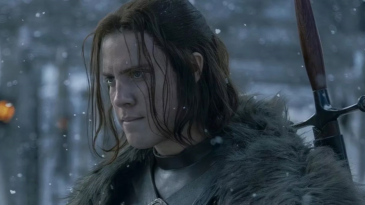 Tom Taylor as Cregan Stark in a scene from HBO's 'House of the Dragon.' He is a young, white man with shoulder-length brown hair pulled back in a half-up ponytail. He's wearing the furs and uniform of the Night's Watch. It's snowing, and he's looking at something very intently.